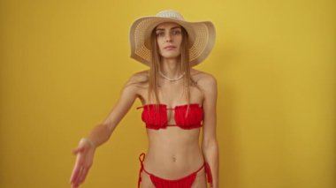 Bikinili bir kadın elleriyle gözlerini kapatıyor. Ciddi ve üzgün bir beyaz kadın. Yazın şapkasıyla gizlenmiş.