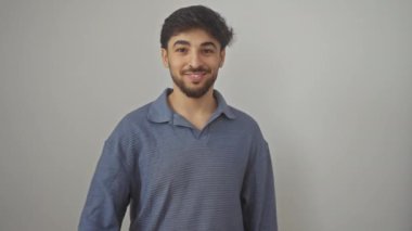 Genç, mutlu, gülümseyen Arap adam işaret veriyor, olumlu onay veriyor, başarının sembolü, izole edilmiş beyaz bir arka planın başında duruyor, mükemmel bir jest.