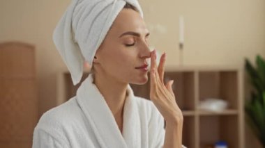 Kafasında havluyla kaplıcaya benzeyen bir sağlık merkezinde cilt bakımı yapan güzel bir genç kadın..