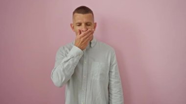 Kafkasyalı genç bir adam esniyor ve pembe bir arka plana yaslanıyor.