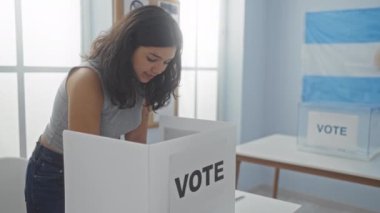 Arjantin 'de seçmen odasında oy veren İspanyol bir kadın. Arka planda oy kullanma kabini ve bayrağı var..