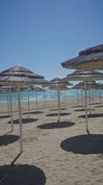 Porto Sezaryen 'de sazdan şemsiyeleri olan boş bir sahil güneşli bir günde İtalya' da sakin manzaralı bir güzellik ve sükunet sergiliyor..