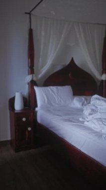 Loş aydınlatılmış bir odada, geleneksel ahşap bir dört direkli yatakta birbirine dolanmış beyaz çarşaflar hoş, kırsal bir atmosferi çağrıştırıyor..