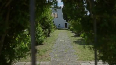 Bereketli yeşil bitkilerle kaplı sakin bir taş yol Puglia, İtalya 'da güneşli bir gökyüzünün altında büyüleyici bir beyaz eve çıkar..