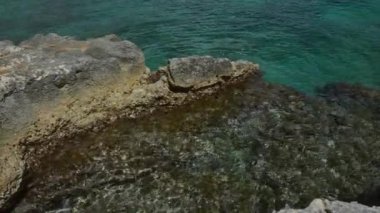 Berrak turkuaz su, Torre Dell 'orso, Puglia, İtalya' daki kasvetli bir sahil sahnesinde engebeli kaya oluşumlarıyla buluşur. Açık hava ve seyahat görüntüleri için mükemmel bir doğal deniz manzarası yaratır..