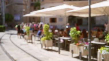 Mallorca City Caddesi 'ndeki bulanık arka planlı açık hava kafenin keyfini çıkaran odaksız insanlar.