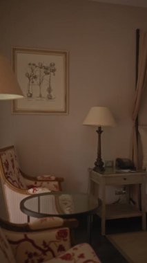 Lüks konaklama ve konforu gösteren büyük yatak odası, komodin, lamba ve sanat eserleri..