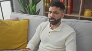 Öfkeli genç İspanyol adam evde hayal kırıklığını ifade ediyor. Elleriyle jesti durduruyor.