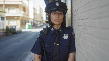 Olgun bir İspanyol polis kadın bir şehir caddesinde ihtiyatlı bir şekilde duruyor, otoritesini ve güvenini yayıyor..
