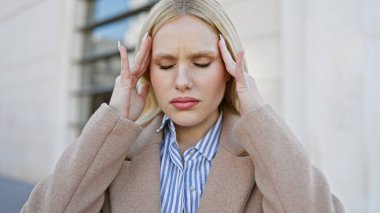 Başağrısı olan stresli genç bir kadın şehir caddesinde duruyor, şehir yaşamındaki zorlukları somutlaştırıyor..