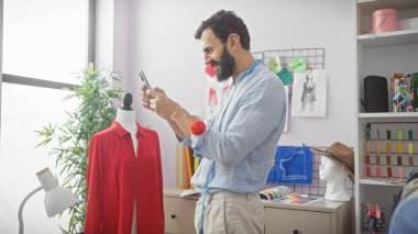 Parlak bir terzide kumaş örneklerini inceleyen sakallı bir adam..