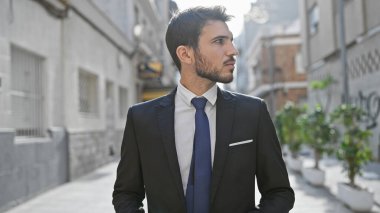 Yakışıklı İspanyol işadamı, şehir caddesinde dikilirken dikkatle başka tarafa bakıyor..