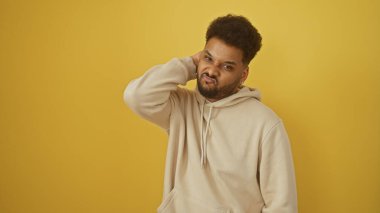 Yakışıklı, sıradan kapüşonlu Amerikalı adam canlı sarı bir arka plana karşı güvenle poz veriyor..