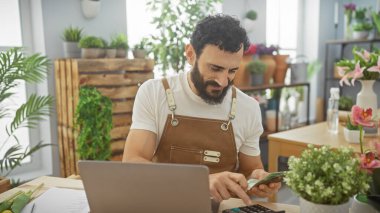 Sakallı adam çiçeklerle ve çiçeklerle çevrili bir çiçekçinin içinde dirhem sayıyor..