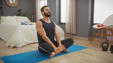 Modern bir yatak odasında yoga minderi üzerinde meditasyon yapan bir adam. İçerde rahatlık ve rahatlık sergiliyor..