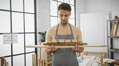 Genç İspanyol bir adam parlak bir atölyede keresteyi inceliyor, ustalığı ve profesyonelliği somutlaştırıyor..