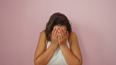 Yüzünü pembe duvara yaslayan kadın renkli tırnaklar gösteriyor.