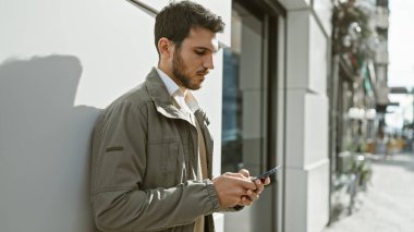 Yakışıklı genç İspanyol adam Sunny City caddesinde akıllı telefon kullanıyor..