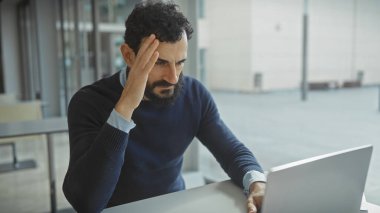 Modern ofiste sakallı stresli bir iş adamı baş ağrısı çekiyor.