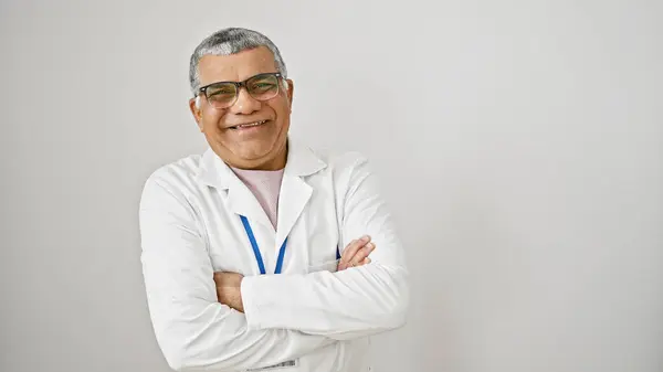 stock image A smiling middle-aged man with grey hair and glasses, wearing a lab coat, stands with his arms crossed against a white background.