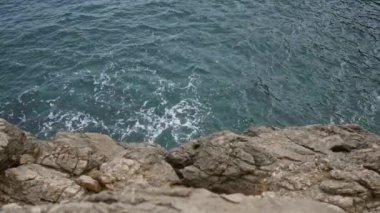 Cala Deia 'daki Mallorca kayalık kıyı şeridi engebeli kayalara çarpan turkuaz deniz dalgalarıyla Akdeniz güzelliğinin manzaralı bir manzarasını sunuyor..