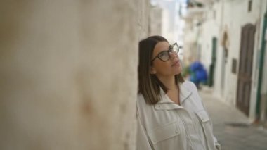 İspanyol kadın gülümsüyor, polignano 'nun büyüleyici sokaklarında taş duvara yaslanmış bir kısrak, puglia, İtalya, neşe ve huzur anı yakalıyor..