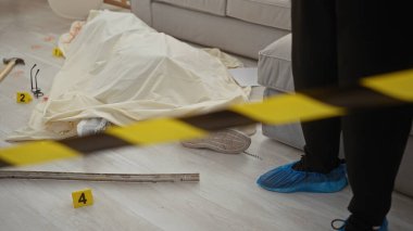 Bir dedektif kanıt işaretleri, çekiç, gözlük ve ayakkabı kılıflarıyla karışık bir suç mahallini araştırır..