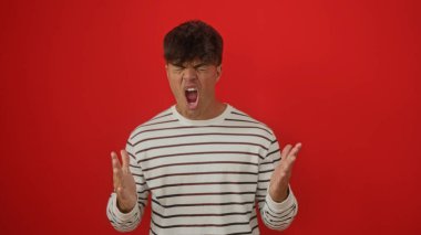 Genç bir İspanyol öfkeyle kırmızı arka plan duvarına karşı bağırıyor..