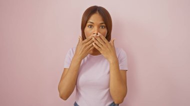 Şaşırmış Afrikalı Amerikalı kadın pembe arka planda ağzını kapatıyor.