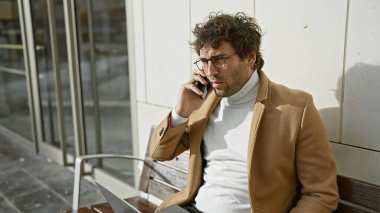 İş kıyafetleri içinde şık bir adam şehirde bir bankta otururken bir telefon görüşmesine katılmış..