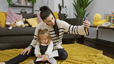 Mother and daughter bonding in living room, woman takes selfie while girl draws, modern home setting. clipart