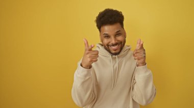 Neşeli Afrikalı Amerikalı adam, parlak sarı bir arka plana karşı kamerayı işaret ediyor..