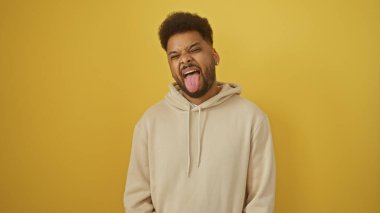 Yakışıklı siyahi adam sarı bir arka planda komik bir yüz ifadesi takınıyor..
