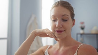 Genç bir kadın, sağlık merkezinin spa odasında, rahat ve güzel görünüyor, doğal sarı saçlarıyla, ev ortamının keyfini çıkarıyor.