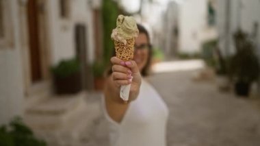 Genç İspanyol kadın Locorotondo, Puglia, İtalya 'da antika bir caddede dondurma külahının keyfini çıkarıyor. Avrupa' nın büyüleyici atmosferini sergiliyor..