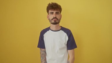 Gülümseyen genç İspanyol adam izole edilmiş sarı bir arka planda başarılı bir iş tokalaşması teklif ediyor.