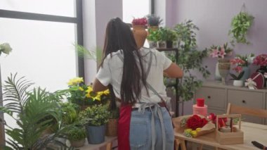 İki kadın canlı bitkiler ve çiçeklerle dolu bir çiçekçide dostça tokalaşıyorlar..