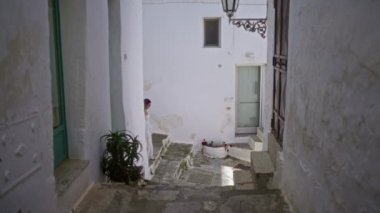 Genç bir İspanyol kadın, Puglia, İtalya 'nın etkileyici eski kasabasında beyaz bir elbise giymiş ve elinde hasır bir sepet taşıyarak yürüyor..