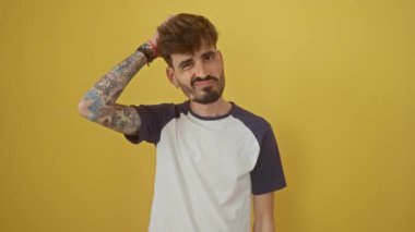 Düşünceli genç İspanyol adam izole edilmiş sarı arka planda duruyor, derin düşünceler, kafa karışıklığı ve şüphe ortaya koyan bir soru. Merak, belirsizlik - kavramsal bir portre.