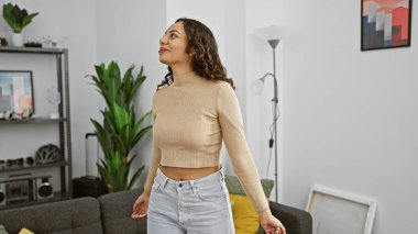 Gündelik giysiler içindeki kendine güvenen bir kadın modern dekorlarla çevrili şık bir oturma odasında bir anlık dinlenmenin tadını çıkarır..