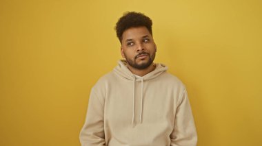 Düşünceli bir Afrikalı Amerikalı 'nın portresi. Günlük bej kapüşonlu, parlak sarı arka planlı..