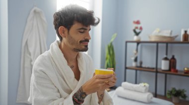 Yakışıklı, sakallı, sıhhatli bir kaplıca merkezinde çay içen yakışıklı bir adam.