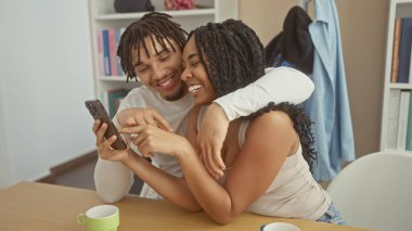 Sevgi dolu bir çift kapalı alanda akıllı bir telefonla neşeli bir anı paylaşıyor, mutluluk ve beraberlik yayıyor..