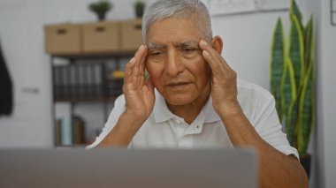 Orta yaşlı, gri saçlı, düşünceli ve endişeli görünen İspanyol bir adam. Arka planda kitaplıklar ve bitkilerle dolu bir ofis ortamında..