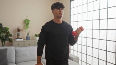 İspanyol bir adam modern bir oturma odasında ağırlık kaldırıyor, evde spor yapıyor..