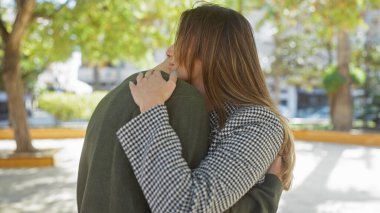 Dışarıdan bir erkeği kucaklayan bir kadın doğal bir arkaplan ile olan ilişkide sevgi ve yakınlık gösterir..