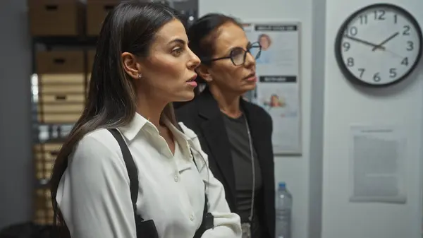 stock image Two professional women in an office analyzing evidence with focus and determination.