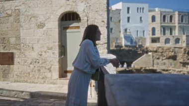Genç bir İspanyol kadın polignano 'nun güzel manzarasından zevk alır. Güneşli bir günde arka planda tarihi binalar bulunan kısrak, puglia, İtalya..