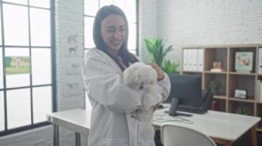 Neşeli bir veteriner, modern bir veteriner kliniğinde kocaman pencereleri olan bir köpeğe sarılıyor..