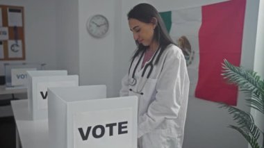 Steteskoplu genç bir İspanyol kadın seçim odasında Meksika bayrağıyla gülümseyerek demokrasiye olan güvenini iletiyor..